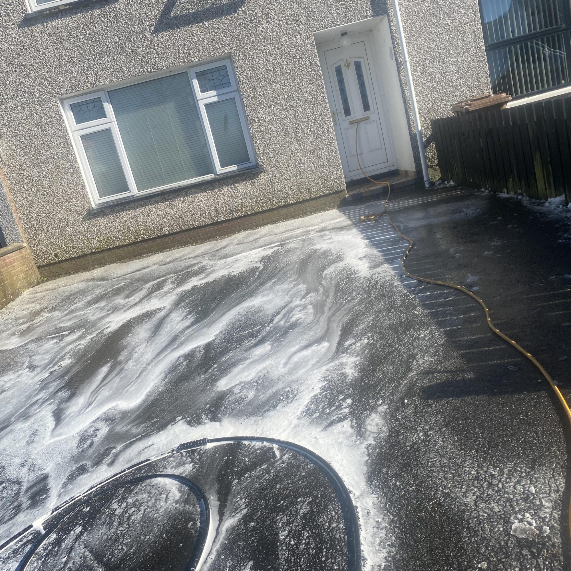 Power washing front drive way of a small house